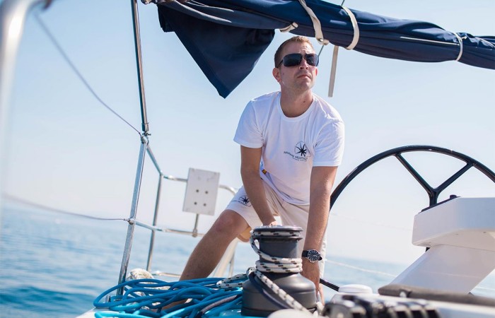 Skipper mentre opera sul winch di una barca a vela